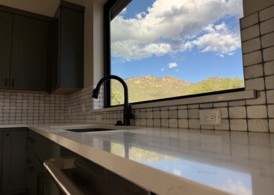 closeup of kitchin sink with tiled backsplash looking out the window to the mountains Custom Home with Lockoff ADU in Buena Vista by S&T Construction
